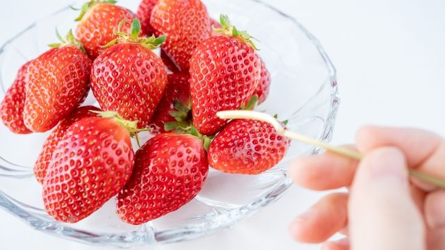 器に持ったいちごをフォークで刺す イチゴを食べるイメージ