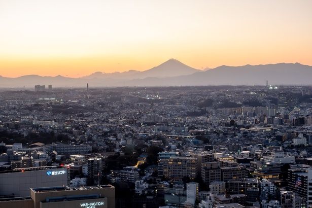 地上154メートルの高さから、街の向こう側に沈む夕日と富士山のシルエットも