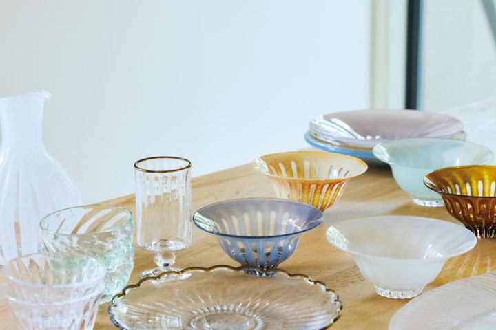 スモーキーな色合いの器はすべて花岡央（ひろい）さんの作品。「器店“千鳥”で出合い、絶妙な色合いにひと目惚れ。平皿や鉢、花器などいろいろと集めています」。キラキラ輝くガラスは食材をみずみずしく見せ、四季を問わず活躍しているそう。茶色の縁がしゃれた器は田井将博（たいまさひろ）さんの作品。「グラスは“カフェオレグラス”という名前で、確かにカフェオレがよく似合います」