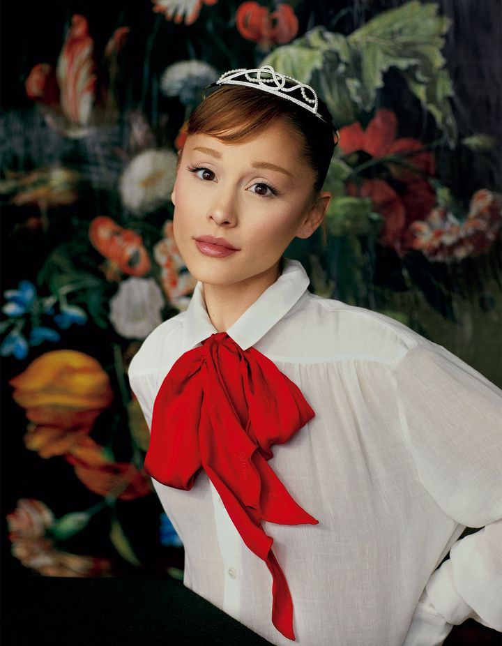 解き放つオーラを背に 大女優の風格を漂わせるスワロフスキーのティアラに、鮮やかなレッドリボンが目を惹くラルフ ローレンのシャツを合わせたグランデ。後世に語り継がれるであろう映画『ウィキッド』のグリンダ役を見事に演じ切った彼女。幼き頃、同ミュージカルをブロードウェイで鑑賞した夢見る少女は、自らの手でその役を掴み、夢を現実のものへと成した。シャツ スカーフ ともに参考商品／RALPH LAUREN COLLECTION（ラルフ ローレン） ティアラ 参考商品／SWAROVSKI JEWELRY（スワロフスキー・ジャパン）