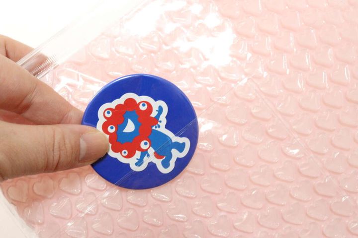 ダイソーのプチプチポーチ（ハート、27.2cm×20cm）の外側のポケットに缶バッジを入れる