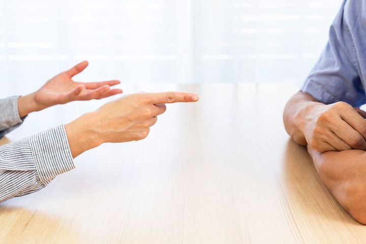 机を挟んで座り、口論している男女