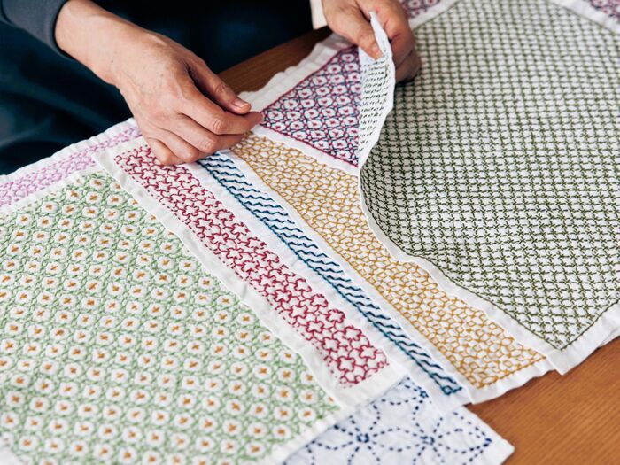 刺し子のキットを楽しむシニア女性の手元。色とりどりの伝統柄を縫い進める様子。100均アイテムで始める刺し子趣味、手仕事で心が整うスローライフ。
