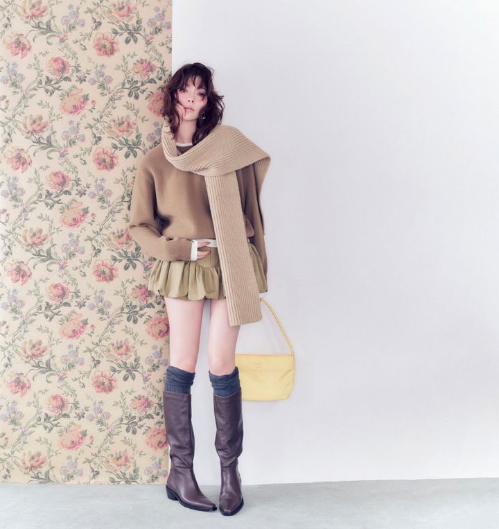 八木アリサさんが、ベージュのフェザーニットにバルーンミニスカートを合わせたレイヤードコーデ。ロングマフラーとブラウンのロングブーツで、まろやかな冬のワントーンスタイルを披露。