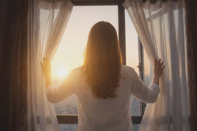 カーテンを開ける女性