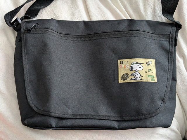 ブラックのメッセンジャーバッグ正面（フラップと前面ファスナーポケット）