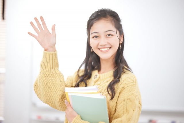 笑顔で手を上げて挨拶する女性