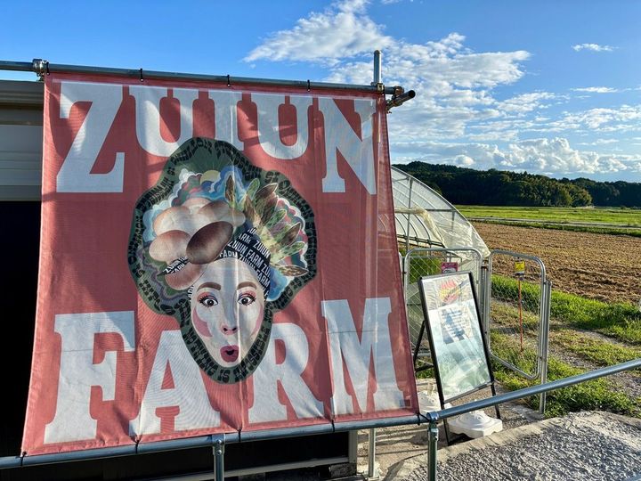 自販機の建物は広大な畑の中にポツンとあるが、ポップなイラストの日除け看板でインパクト抜群