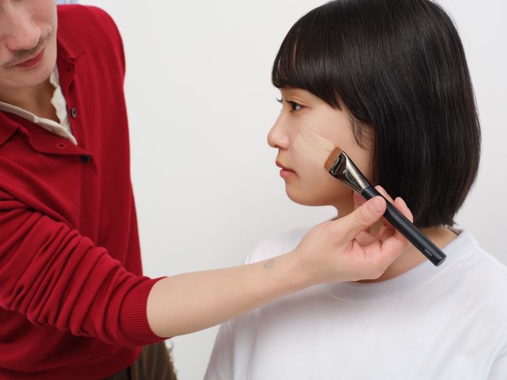 ブラシで顔の中心から外側に向かって、均一になるように伸ばしていく