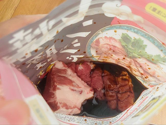 袋上部にある「あけくち」を切って袋の中に豚肉を入れ、ジッパーを閉じて軽くもむ