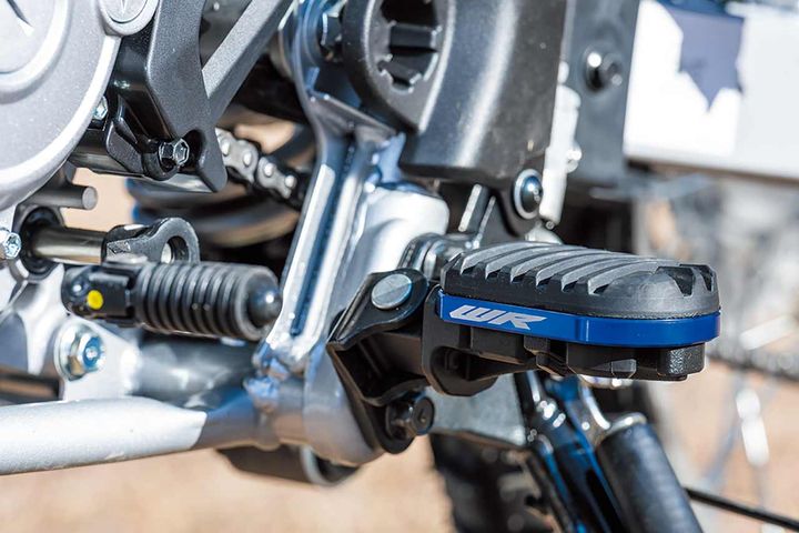 WRロゴ入りアドベンチャーフットペグ。街乗りは防振＆靴底保護のゴムカバーを装着し、林道では工具不要でステンレスブレードに簡単切替