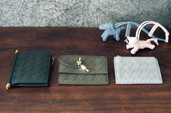 上段、犬と猫をモチーフに、細いコードを編み上げた手の込んだイントレチャート。心がなごむ可愛い佇まいと、優しいパステルカラーで春のムードを先取り。チャーム 各￥93,500、下段右から、スタイリッシュなライトグレー。後ろにカード入れが付いたスタンダードな仕様。柔らかなレザーで出し入れしやすい。カードケース［H8.2×W12×D0.5、カード入れ3］￥88,000、ゴールドカラーのノットをアクセントにしたシンプルさがグッド。前にフラップポケット、後ろにジッパー付きコイン入れとカードスロットが。［H8.6×W12.5×D1、カード入れ3］￥136,400、深みのあるグリーンがクラシカル。メタルのノットディテールがついたコンパクトな二つ折り。ウォレット［H11.5×W10×D1、カード入れ6］￥124,300（すべてボッテガ ・ヴェネタ／ボッテガ ・ヴェネタ ジャパン）