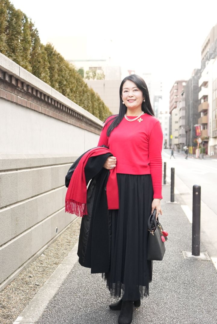 コートを脱いでみると鮮やかな赤ニットが際立ち、顔まわりが明るく映えます。