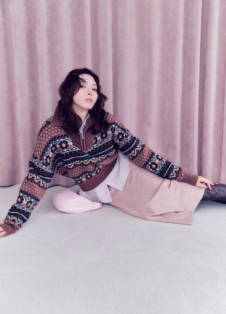 スモーキーなブラウンのジップアップニットにピンクのタイトスカートを合わせた冬コーデ。ブラウンからピンクへとつながるグラデーション配色で、甘さと大人っぽさを両立したスタイリング。