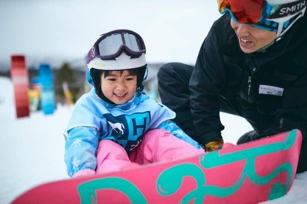 インストラクターと一緒にボードをセット。笑顔あふれる雪上デビュー