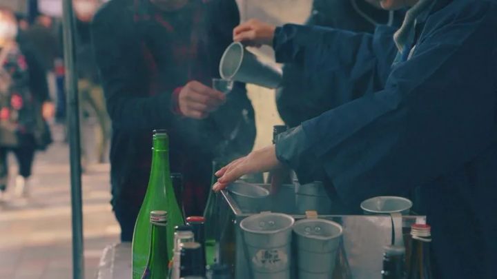 スタッフがカップに日本酒を注ぐ試飲提供シーン