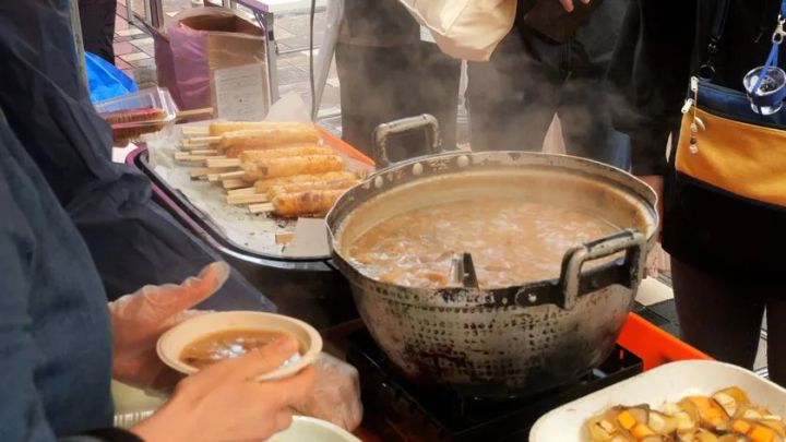 煮込み料理を盛り付けるフードブースの調理シーン