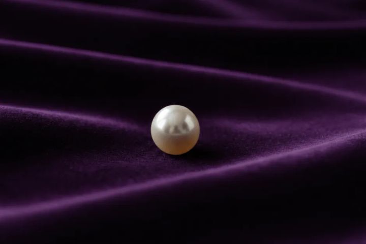 紫ベルベットに置かれた白い真珠1粒