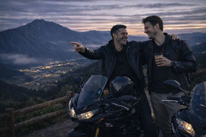 夕暮れの山間で大型バイクを囲んで談笑するツーリングシーン