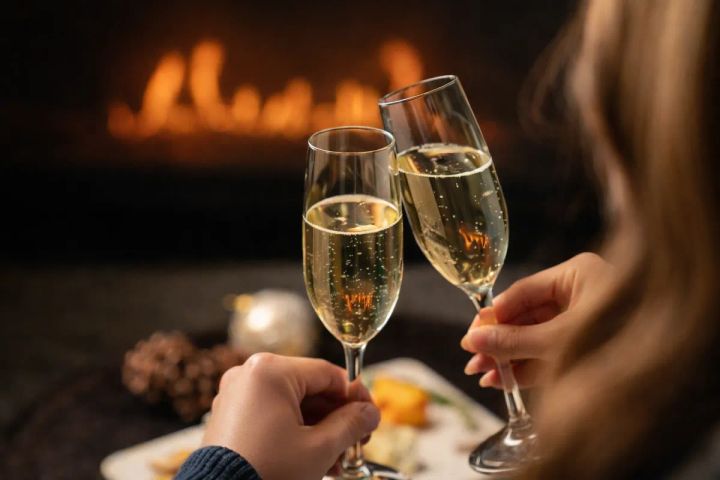 暖炉の前で乾杯する記念日ディナーのイメージ