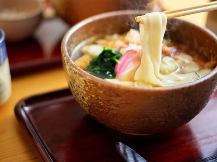 湯気が立つきしめんを箸で持ち上げた温かい食事メニュー