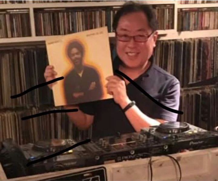 DJ機材前でレコードを掲げる持田騎一郎氏