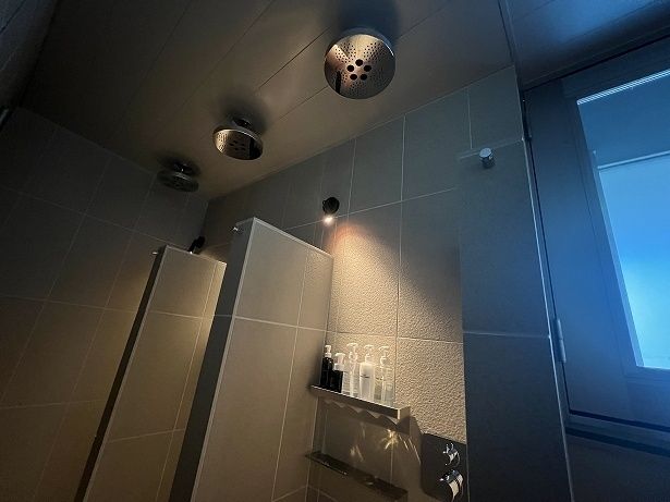 温かいお風呂の前に天井固定タイプのシャワーブースが3つ並ぶ