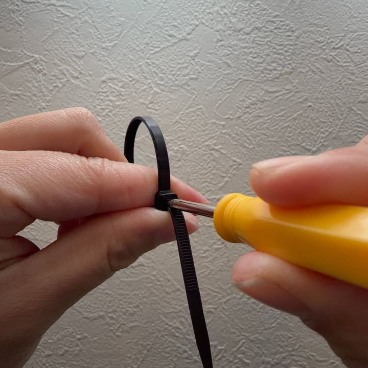 結束バンドのつめにマイナスドライバーを差しているところ