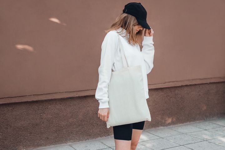 白いトートバッグを持つスポーティーなファッションの女性