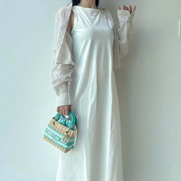 ディオールのかごバッグを持つ白いワンピースの女性