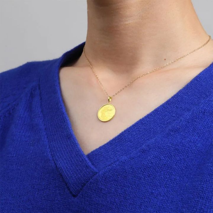 ロイヤルブルーのニットに着用した純金コインペンダント