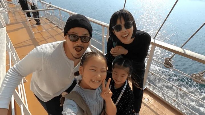 クルーズ船デッキで笑顔の家族が記念撮影する様子