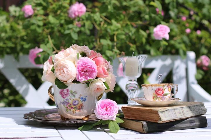 ヴィンテージのポットに生けたたおやかなバラ。バラがあるとお茶の時間がいっそう優雅になります。背景のフェンスのバラも葉も素敵。