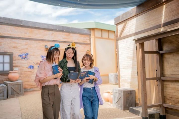 女性グループが冒険の書を持ってアトラクションを楽しむ様子