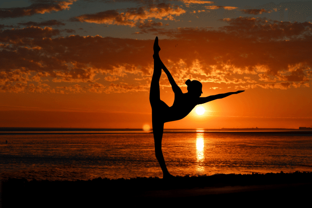 夕日の前でヨガする女性