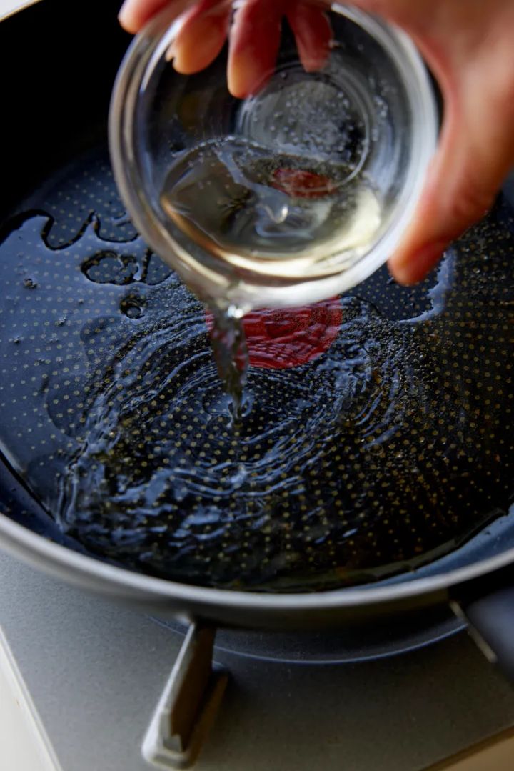 フライパンに白ワインを入れる