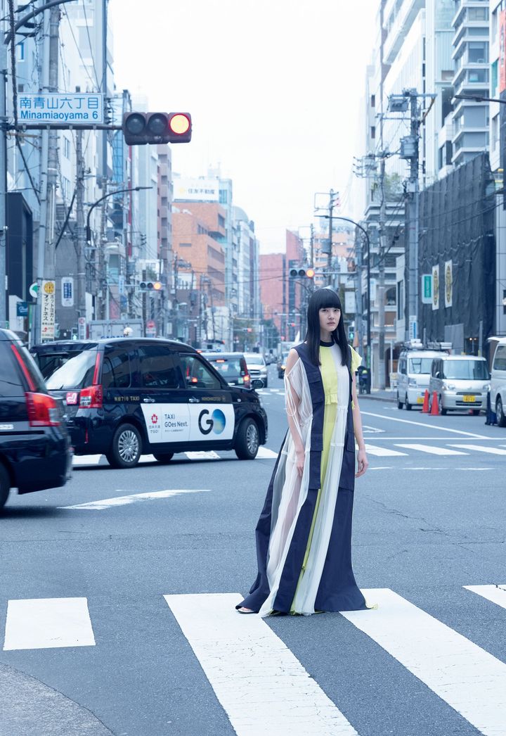 驚きと愛着を生み出す、「安心と裏切りのバランス」 <br /> さまざまな素材や色が織りなす洗練のリズム。ボリューム豊かな布がダイナミックに流れ、揺れるドラマティックなロングドレスも、不思議と東京のグレイな街並みにマッチして。ロングドレス ￥308,000 サンダル ￥88,000╱ともにSACAI（サカイ）