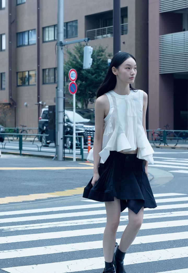 多くの人がひと目でサカイだと認識するアイコニックなペプラム使いもシンプルに、力強く。ペプラムトップ ￥253,000 ラッフルスカート ￥176,000 ブーツ ￥132,000╱すべてSACAI（サカイ）