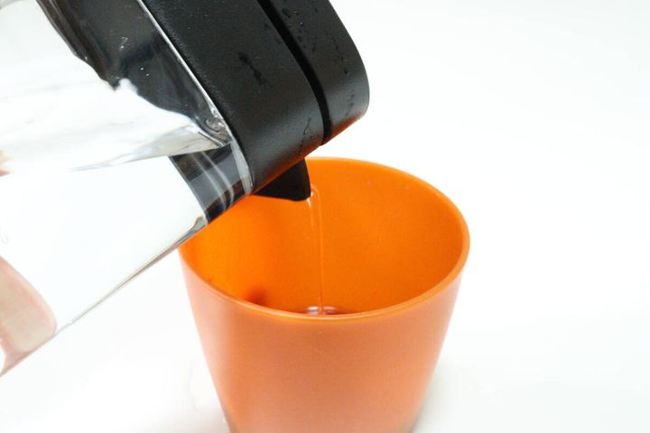ダイソーの横置きできる冷水筒（取っ手なし、1.6L、ブラック）で飲み物を注ぐ
