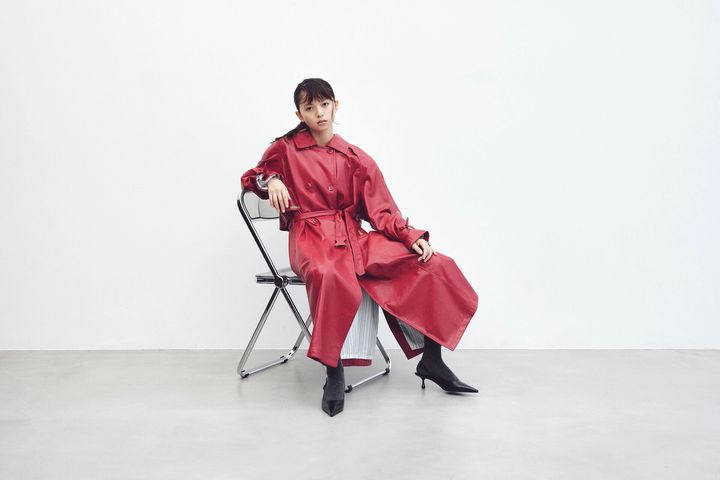 光沢のある赤レザーコートに黒タイツとキトゥンヒールを合わせた、隙のない冬の最新ルック。どこかアンニュイでドラマチックな視線が印象的な別カット。