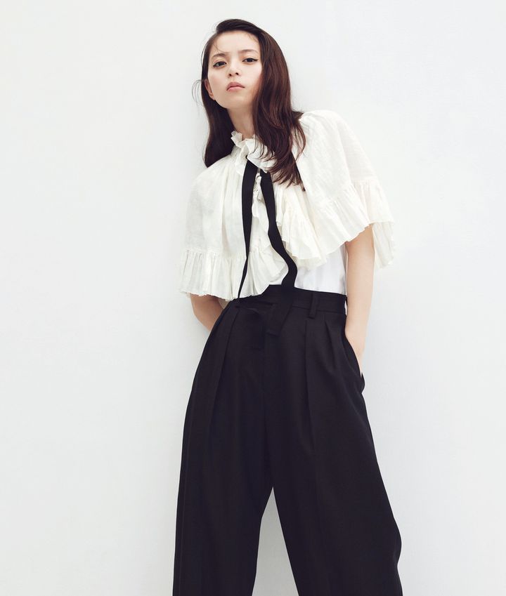 白のフリルケープに黒のハイウエストワイドパンツを合わせた、クラシカルでマスキュリンなモノトーンスタイル