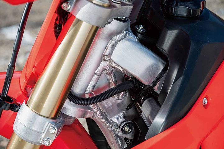 2025年モデルはフレーム構成部品の約70％を新設計し、縦剛性を約4％向上。これにより荒れた路面での車体挙動を抑え、サスペンション本来の性能をより引き出している。SHOWA製サスペンションも大幅に刷新され、トップブリッジやボトムブリッジ、ステムパイプ、フロントアクスルシャフトなどを新設計。全域でスムーズな作動感を実現。さらに、走破性に大きく影響するリンク構造は形状やレバー比を変更し、剛性アップとクッション作動性、ボトムタフネスを向上。エンジン、吸排気系、ブレーキ、外装パーツ形状も刷新され、リアクッションの整備性も改善されている。リンク形状の変更も走破性能の向上に寄与しており、ライダーからの評価も高い