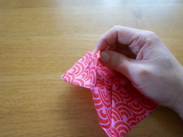 折った角をつまみ上げ、裏中央の角を引き出します。