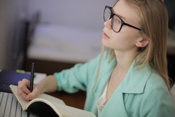 ノートに文字を書く女性
