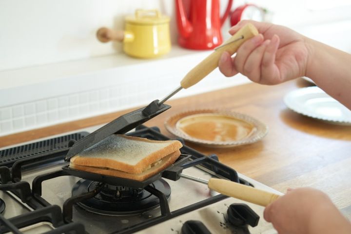 直火式ホットサンドメーカーで食パンを挟む女性の手元
