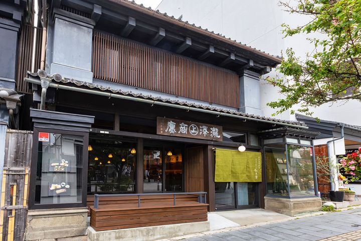 浅緑色の暖簾と信州ゆかりの書家・秋山白巌による木の看板が掲げられている