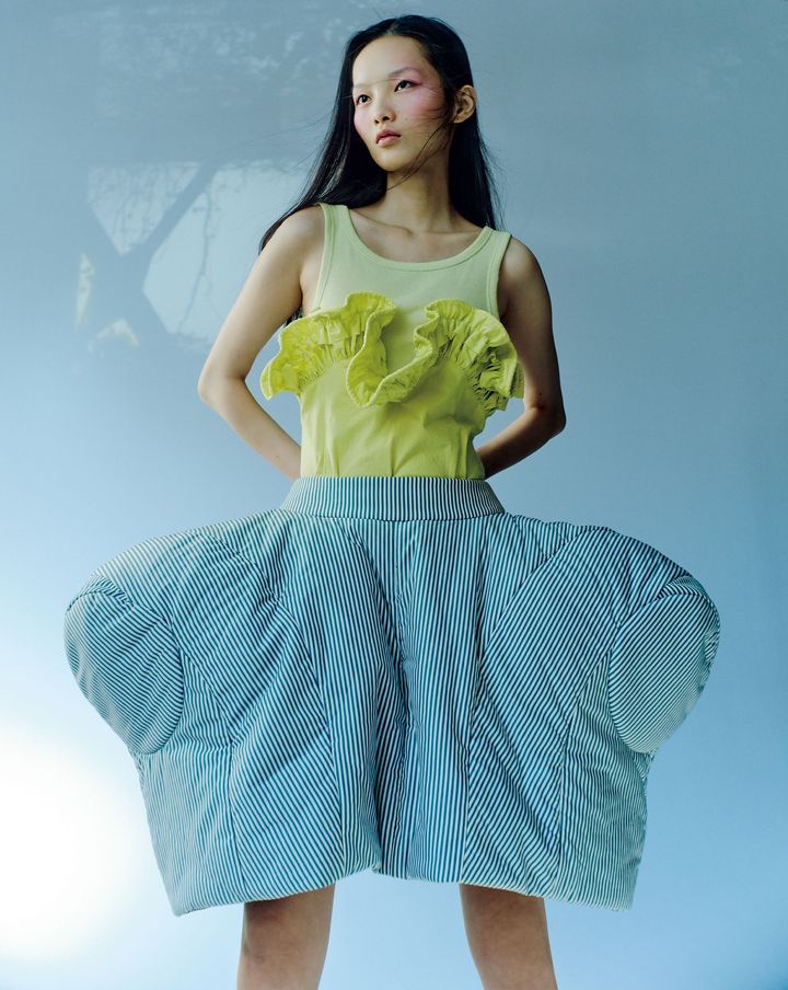 パンキッシュに煌めくバレエの世界 <br /> デザイナーの幾左田千佳はバレエに触れて育ち、2014年に自身の名を冠したブランドを始動。バレエのエレガンスとパンキッシュな精神を表現している。26年春夏は「理想の身体の形」を追い求め、アーティストの林ひかりともコラボレーション。フリル付きのタンクトップに合わせた構築的なスカートは、バレエダンサーの立ち姿や、体の内側から沸き起こるエネルギー・緊張感をイメージした佇まいが印象的。タンクトップ ￥31,900 スカート 参考商品╱ともにCHIKA KISADA（チカ キサダ）