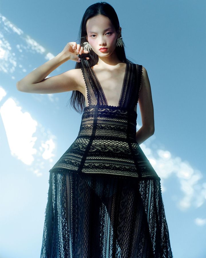 フェティッシュに探るボディと服の新しい関係 <br /> 国内ブランドで経験を積んだ舟山瑛美が2020年に設立。女性の体の造形美を軸にしたものづくりを続けている。26年春夏は「byR」の支援を受けてショーを開催。フォトグラファー、イリナ・イオネスコと現代美術家、レベッカ・ホルンに着想を得てより大胆に肌を露わにし、職人技を駆使した手の込んだディテールも見せた。9種類のレースを刺繍ではぎ合わせた素材を用いたロングドレスは、ブランドの持つセンシュアルな魅力を存分に発揮。ドレス ￥550,000 ピアス ￥31,900╱ともにFETICO（ザ・ウォール ショールーム）