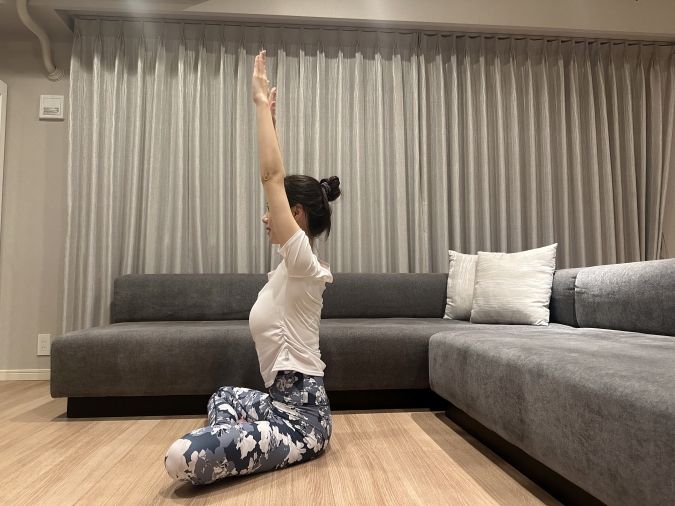 椅子に座り、両腕を天井に向かって伸ばす。