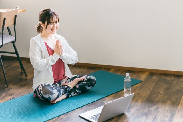 パソコンを見ながらヨガする女性 オンライン教室イメージ